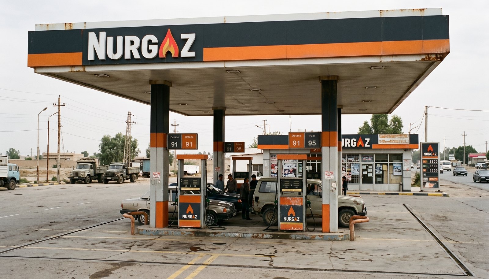 A worn filling station with a dark canopy and orange band reading NURGAZ, orange pumps, older cars filling up and dump trucks parked behind